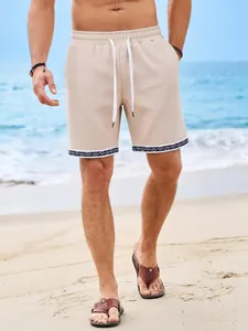 Dettaglio dei pantaloncini da spiaggia beige in maglia a nido d'ape con bordo geometrico