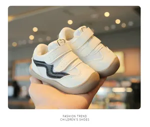 Primo piano di scarpine da primi passi bianche con motivo a onde nere e velcro.