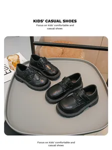 Dettaglio di scarpe in pelle nera stile inglese per bambini su vassoio grigio.