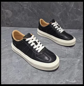 Detailed view of black leather thick-soled sneakers with white laces on grey marble.