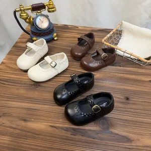 Klassische Mary Jane Schuhe für Kinder in Schwarz, Braun und Weiß auf Holztisch