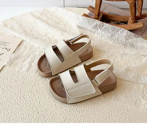 Detailansicht von beige Kinder-Sandalen mit Klettverschluss und geprägtem Markenlogo.