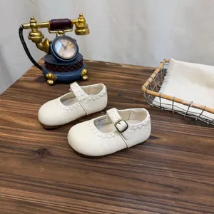 Detailansicht der weißen Vintage Mary Jane Kinderschuhe auf einem rustikalen Holztisch.