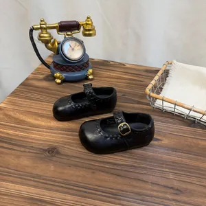 Klassische schwarze Retro-Mary-Jane-Lederschuhe für Mädchen auf einem Vintage-Holztisch