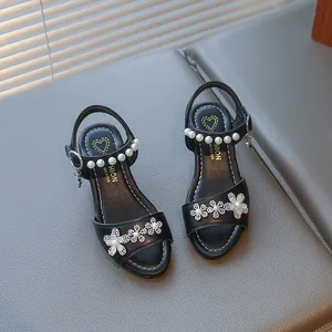 Detail of girls' black sandals decorated with pearls and rhinestone flowers.