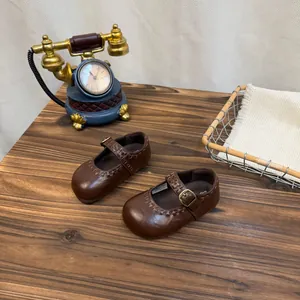Detailaufnahme von braunen Retro-Kinder-Mary-Janes auf einem klassischen Holztisch.