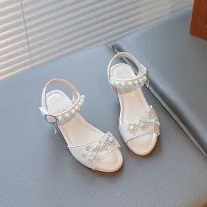 Elegant detail of pearl ankle straps and rhinestone flower accents on girls sandals