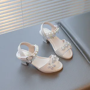 Close-up of white girls' princess sandals with rhinestone flowers and pearl straps.