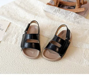 Elegante Detailansicht schwarzer Leder-Sandalen für Kinder auf weißer Spitze