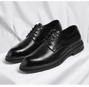 Detailed close-up of black perforated leather business dress shoes on white background fabric