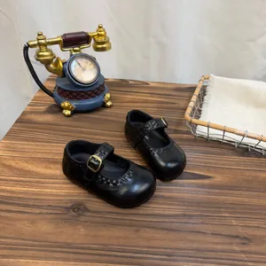 Retro schwarze Mary-Jane-Lederschuhe für Mädchen auf einem rustikalen Holztisch