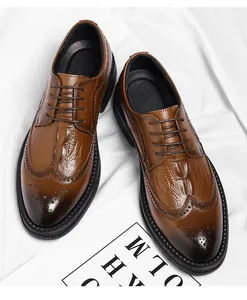 Macro view of men's brown crocodile texture brogue shoes with wingtip detailing.