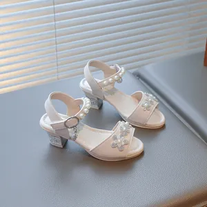 Detailed view of girls cream sandals with rhinestone flowers and pearl ankle strap