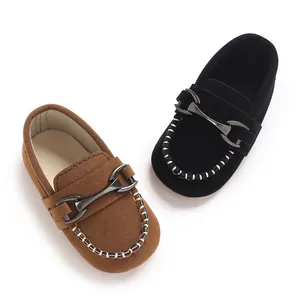 Close-up of matte leather baby loafers with metal buckle and stylish contrast stitching