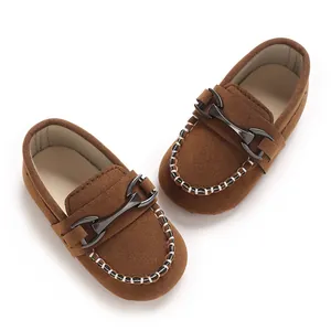 Detailed view of brown baby loafers featuring a metal buckle and frosted leather texture.