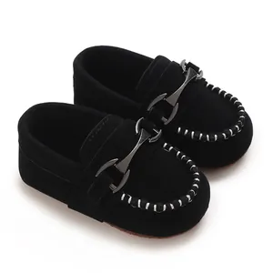 Detailed view of black suede baby loafers with horsebit buckle and white stitching