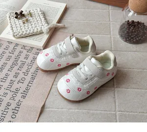 Dettaglio di scarpe bianche per bambina con ricamo floreale rosa e bordo in pizzo