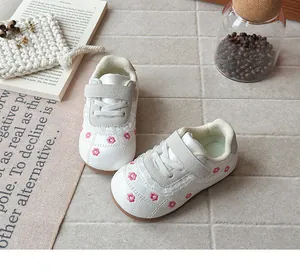 Vista dettagliata di scarpe primi passi bianche da bambina con ricamo floreale rosa