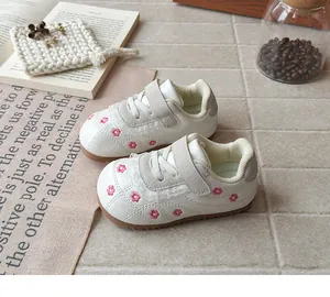 Dettaglio scarpe da ginnastica bianche da bambina con ricamo di fiori rosa e pizzo