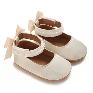 Nahaufnahme von Baby-Prinzessin-Schuhen mit Perlenspitze und eleganten Satinschleifen