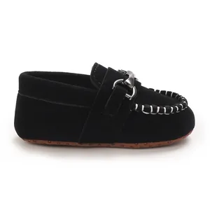 Detail shot of black frosted leather baby loafers with metal buckle and white stitching.
