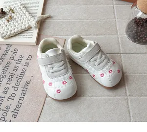 Dettaglio di scarpe bianche da bambina con ricami floreali rosa e pizzo delicato