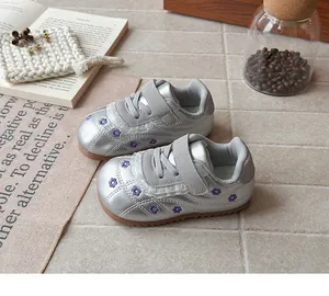 Dettaglio di sneakers argento per bambina con ricami floreali e suola morbida in scena accogliente.