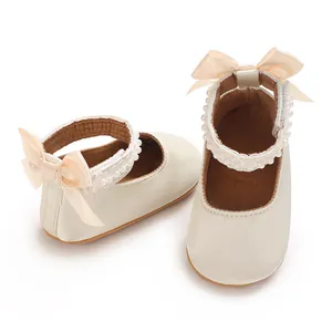 Detailansicht von cremefarbenen Baby-Prinzessin-Schuhen mit Satinschleifen und Perlen.