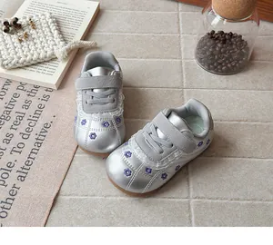 Dettaglio di sneaker argentate per bambine con ricami floreali viola e bordo in pizzo
