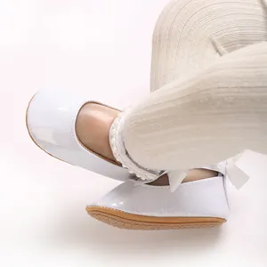 Vue détaillée de chaussures pailletées blanches pour bébé avec bride en perles et nœud.