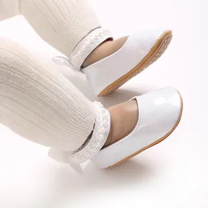 Détail de chaussures bébé Mary Jane blanches pailletées avec perles et nœud