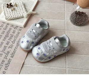 Dettaglio ravvicinato scarpe bimba stile balletto argento con ricami floreali viola.