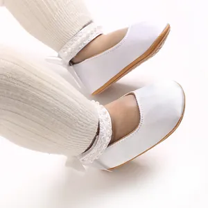 Detailaufnahme von weißen Baby-Prinzessinenschuhen aus Satin mit Perlen und Schleifen