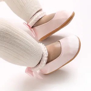 Detailaufnahme von rosa Satin-Prinzessinenschuhen für Babys mit Perlenriemen und Schleife.