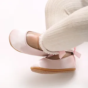Nahaufnahme von rosa Satin-Babyschuhen mit Perlen und Schleifen an kleinen Babyfüßen