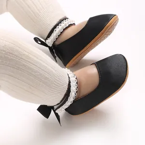 Detailansicht der schwarzen Baby-Prinzessinenschuhe mit Perlenspitzenbändern und Schleifen.