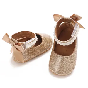 Chaussures de marche dorées à paillettes pour bébé fille avec nœud et bride à perles.
