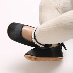 Nahaufnahme von schwarzen Baby-Prinzessinenschuhen mit Perlenriemen und weicher Sohle.