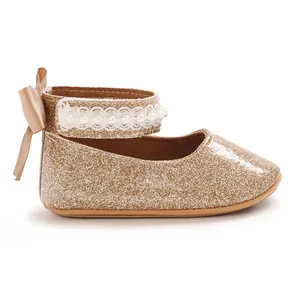 Vue latérale de chaussures de bébé pailletées d'or avec dentelle perlée et nœud