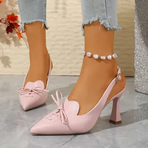 Detail of pink pointed-toe slingback sandals with elegant bow accents on a model.