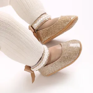 Détail de chaussures de marche pour bébé dorées à paillettes avec perles et nœuds