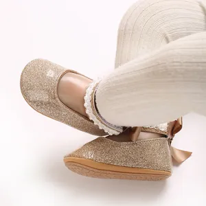 Gros plan de chaussures de bébé fille à paillettes dorées avec perles et ruban chic