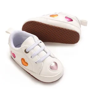 Gros plan de baskets blanches pour bébé avec cœurs colorés et semelles antidérapantes