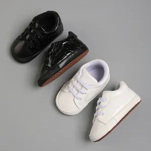 Chaussures de marche souples pour bébé en noir et blanc pour nourrissons de 0 à 18 mois.
