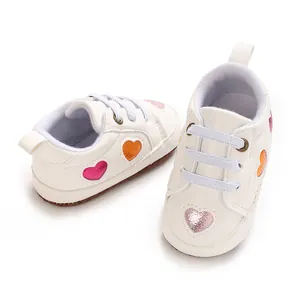 Vue de côté de baskets blanches pour bébé avec écussons cœurs scintillants pour filles