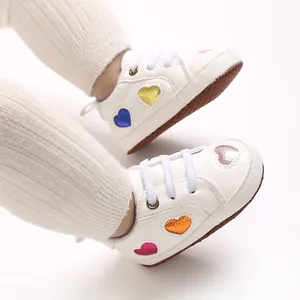 Gros plan de baskets blanches pour bébé avec motifs de cœur métalliques