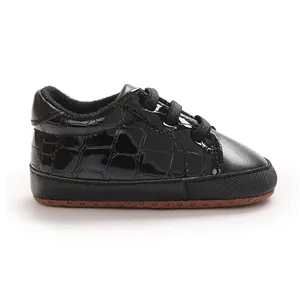 Vue de profil d'une chaussure pour bébé noire avec motif crocodile et semelle souple