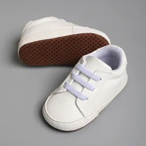 Vue détaillée de chaussures de marche pour bébé blanches avec semelle souple brune.