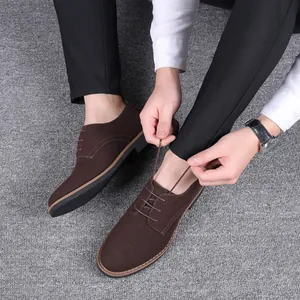 Vue de dessus d'un homme attachant des chaussures décontractées en daim marron sur tapis.