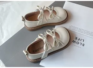 Elegantes zapatos beige para niña con doble lazo y suelas marrones suaves en detalle